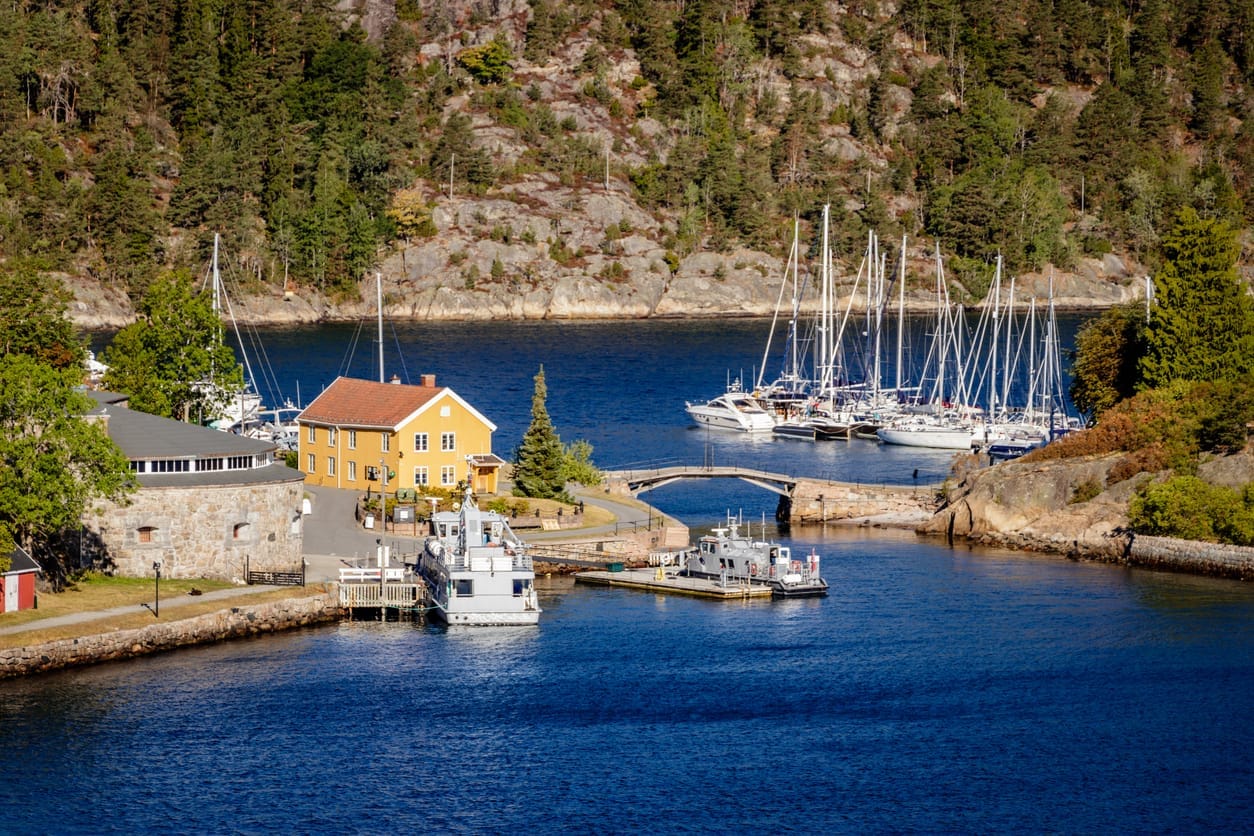 Gult trehus, båthavn og granittsvaberg ved Oslofjorden