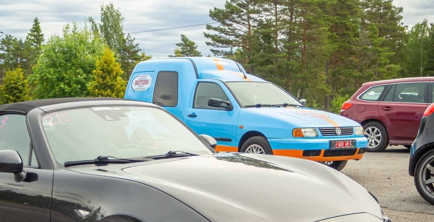Den lyseblå Caddyen parkert ved siden av en sportsbil
