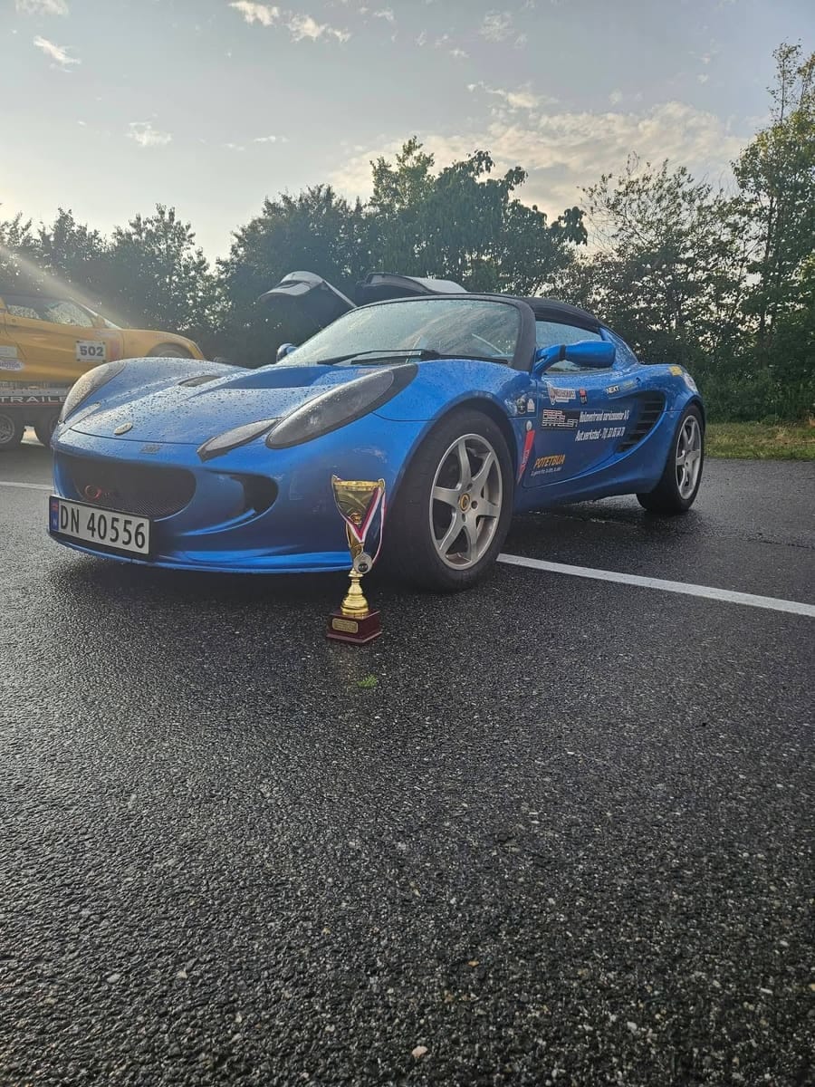 Blå Lotus Elise med pokal på bakken foran