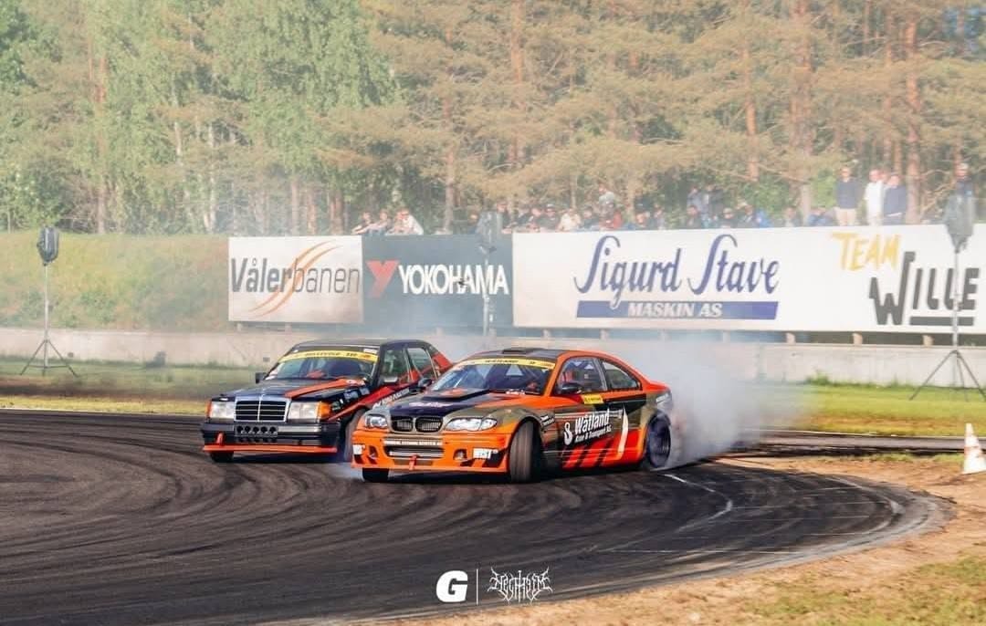 To biler i drift side om side på banen
