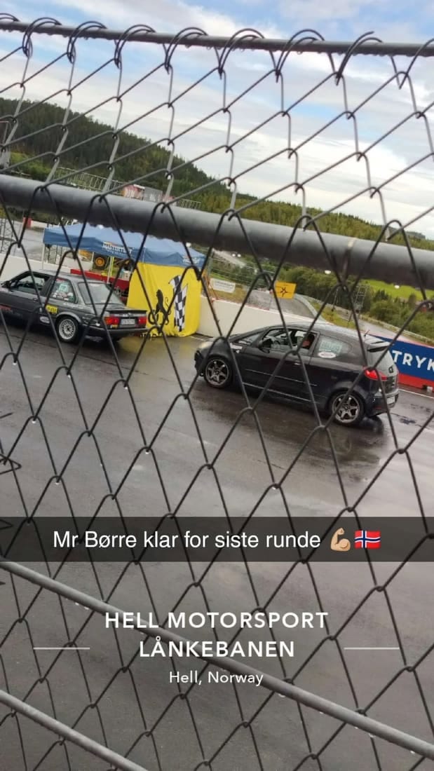 Biler på banen sett gjennom gjerdet før siste runde