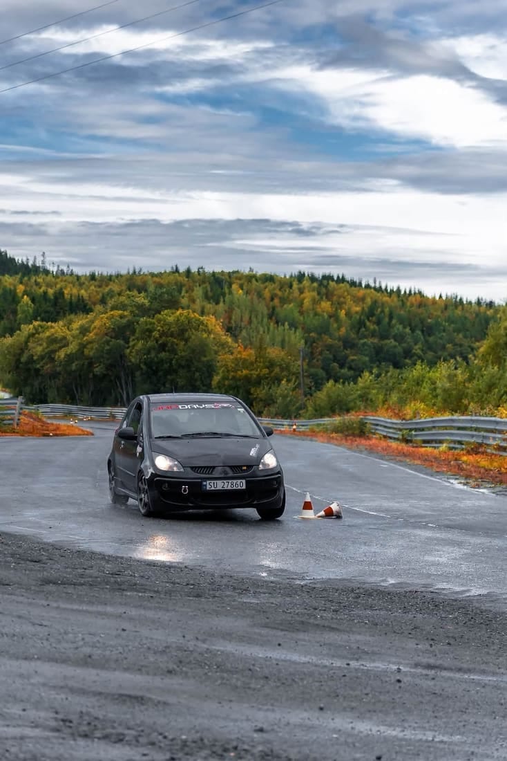 Bil i autoslalom med høstskog i bakgrunnen